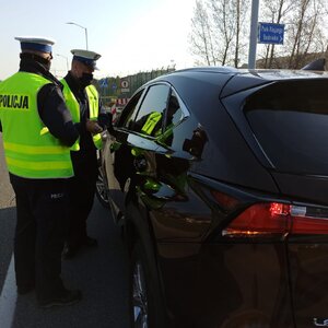 zdjęcie kolorowe: dwóch policjantów katowickiej drogówki podczas kontroli pojazdu osobowego