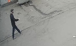 zdjęcie kolorowe: screen z monitoringu giełdy na który jest szczupły mężczyzna ubrany na czarno idący ulica