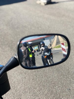 zdjęcie kolorowe: odbicie w lusterku bocznym motocykla kontroli drogowej przeprowadzanej przez policjantów