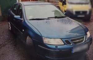 zdjęcie kolorowe: odzyskany samochód osobowy marki Saab przed garażem, w którym ukryli go złodzieje