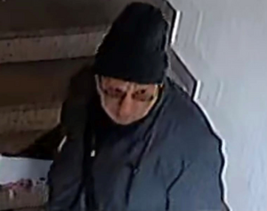 zdjęcie kolorowe: na schodach klatki schodowej widoczny m
starszy mężczyzna ubrany w granatową kurtkę, czarna czapkę i okulary korekcyjne z brązowymi szkłami