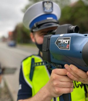 zdjęcie kolorowe: policjant katowickiej drogówki wykonujący pomiar urządzeniem TruCam, służące do pomiaru prędkości pojazdu