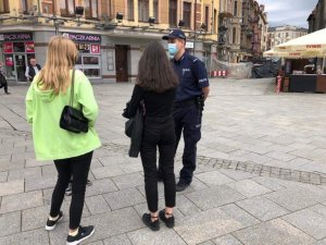 zdjęcie kolorowe: policjant rozmawiający z kobietami na chodniku