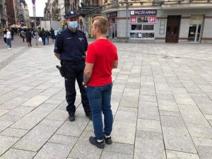 zdjęcie kolorowe: policjant rozmawiający z chłopakiem w czerwonej koszulce