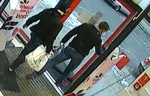 zdjęcie kolorowe: dwóch mężczyzn podejrzewanych o kradzież kosmetyków drogerii wychodzących ze sklepu