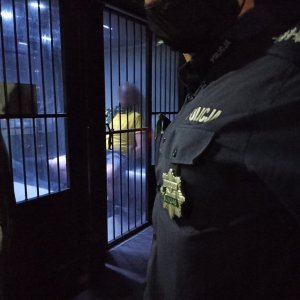 zdjęcie kolorowe:  katowicki policjant przy samochodzie, w którym umieszczono zatrzymanego pseudokibica