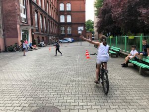 zdjęcie kolorowe: dziewczynka na rowerze sygnalizująca zamiar skrętu w lewo