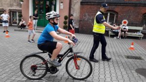 zdjęcie kolorowe: policjant i chłopiec na rowerze podczas egzaminu na kartę rowerową