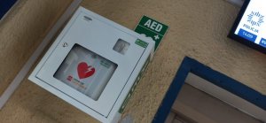 zdjęcie kolorowe: AED zawieszone na ścianie w punkcie przyjęcia interesantów katowickiej komendy