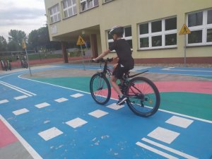 zdjęcie kolorowe: uczeń na rowerze podczas egzaminu na kartę rowerową wykonując jazdę na wprost