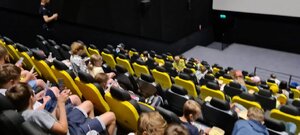 zdjęcie kolorowe: dzieci siedzące na fotelach w kinie podczas profilaktycznego spotkani z policjantami