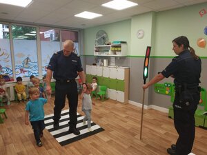 zdjęcie kolorowe: policjant i policjantka z komisariatu I podczas nauki dziecka przechodzącego przez przejście dla pieszych