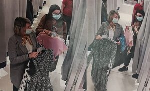 zdjęcie kolorowe: dwie kobiety wychodzące z przymierzalni z ubraniami na rękach. starsza kobieta ubrana w szary płaszcz i biała koszulę, włosy koloru blond, farbowane ze znacznym odrostem, z maseczka na twarzy. Młodsza ubrana w brązowy płaszcz, czarne spodnie, czarne buty sportowe, na twarzy okulary korekcyjne, maseczka ochronna, włosy ciemne długie