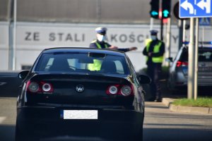 zdjęcie kolorowe: policjant katowickiej drogówki nakazuje kierującemu samochodem osobowym jechać w prawo