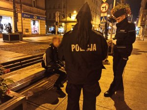 zdjęcie kolorowe: umundurowani policjanci legitymujący osobę nietrzeźwą w centrum Katowic