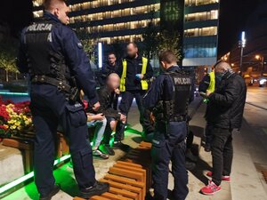 zdjęcie kolorowe: umundurowani policjanci legitymujący osoby przy Placu Kwiatowym w Katowicach