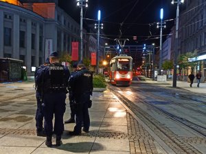 zdjęcie kolorowe: umundurowani policjanci  w centrum Katowic na tle teatru i nadjeżdżającego tramwaju