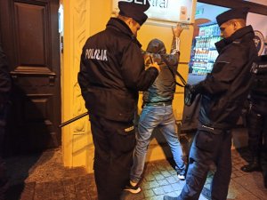 zdjęcie kolorowe: umundurowani policjanci legitymujący mężczyznę, podejrzanego o popełnienie przestępstwa w centrum Katowic