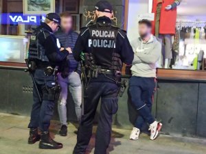 zdjęcie kolorowe: umundurowani policjanci legitymujący dwie osoby w centrum Katowic