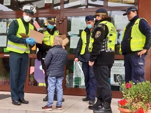 zdjęcie kolorowe: katowiccy policjanci, strażnicy miejscy i funkcjonariusze inspekcji transportu drogowego przed szkołą podstawową rozdający elementy odblaskowe pierwszoklasistom