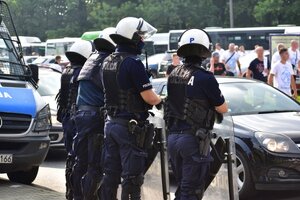 2 - zdjęcie kolorowe: czterech umundurowanych policjantów oddziału prewencji nadzorujący przejście kibiców