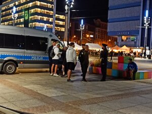 zdjęcie kolorowe: policyjny radiowóz i umundurowani policjanci na rynku w Katowicach przeprowadzający interwencję