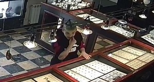 zdjęcie kolorowe: młody mężczyzna stojący przy ladzie u jubilera, ubrany w sportowa bluzę dresową, włosy koloru jasnego zafarbowane na zielono