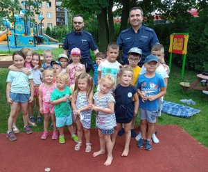 zdjęcie kolorowe: dzielnicowi z komisariatu VII Policji w Katowicach podczas pamiątkowego zdjęcia z przedszkolakami na placu zabaw