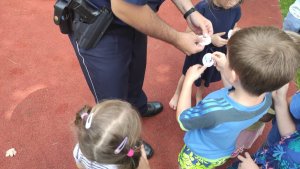 zdjęcie kolorowe: dzielnicowi z komisariatu VII Policji w Katowicach rozdają naklejki  dot. bezpieczeństwa przedszkolakom