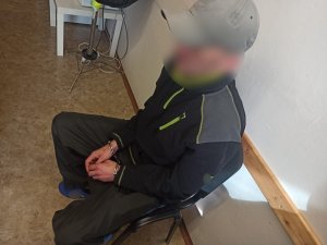 zdjęcie kolorowe: zatrzymanym mężczyzną podejrzanym o fałszywy alarm siedzący na krześle podczas składania wyjaśnień