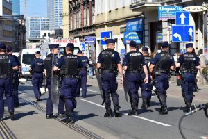 zdjęcie kolorowe: policjantci oddziału prewencji nadzorujący przemarsz uczestników zgromadzenia
