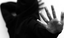 zdjęcie czarno-białe: rozmyty wizerunek kobiety zasłaniającej jedną ręka twarz,druga ręka wyciągnięta do przodu z otwarta dłonią