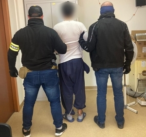 zdjęcie kolorowe: dwóch policjantów słuzby kryminalnej z zatrzymanym 20-letnim mężczyzną