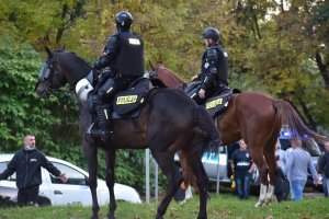 zdjęcie kolorowe: policjanci w służbie konnej podczas zabezpieczenia meczu nadzorujący przemarsz kibiców