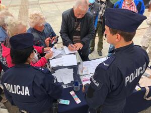 zdjęcie kolorowe: policjanci katowickiej komendy na stanowisku profilaktycznym podczas rozmów z seniorami