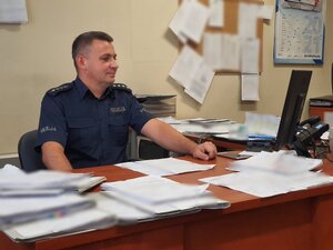 zdjęcie kolorowe: aspirant sztabowy Dawid Koryciński siedzący za biurkiem