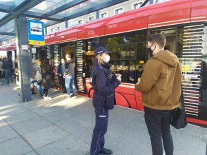 zdjęcie kolorowe: katowicka policjantka podczas rozmowy z młodym mężczyzną na przystanku tramwajowym