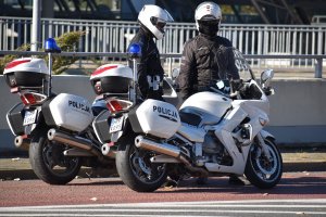 zdjęcie kolorowe: policjanci drogówki przy motocyklach służbowych zabezpieczający przemarsz