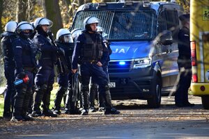 zdjęcie kolorowe: grupa policjantów oddziału prewencji przy radiowozie na parkingu