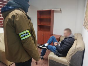 zdjęcie kolorowe: nieumundurowany policjant z zatrzymanym mężczyzną podejrzanym o posiadanie narkotyków, który siedzi na kanapie