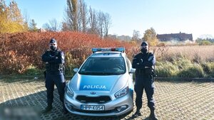 zdjęcie kolorowe: sierż. szt. Rafał Wcisło i sierż. Kamil Marcela stojący przed policyjnym radiowozem