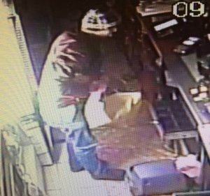 zdjęcie kolorowe:  włamywacz podczas kradzieży w sklepie