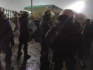 zdjęcie kolorowe: policjanci oddziału prewencji z kibicami drużyny przyjezdnej przy bramo furtach stadionu