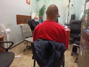 zdjęcie kolorowe: jeden z zatrzymanych siedzący na krześle w pokoju  podczas czynności w katowickiej komendzie przeprowadzanych przez policjanta wydziału kryminalnego