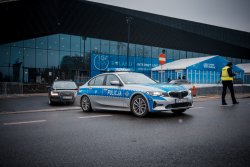 zdjęcie kolorowe: policyjny radiowóz pilotujący samochód przed Międzynarodowym Centrum Kongresowym w Katowicach