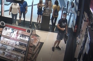 zdjęcie kolorowe: mężczyzna ubrany w krótkiej jeansowe niebieskie spodenki i czarna koszulkę z krótkim rękawem w drogerii przy sklepowej półce