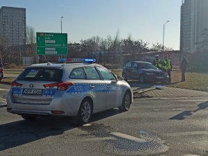 zdjęcie kolorowe: policyjny radiowóz, samochód BMW i dwóch policjantów wykonujacych pomiar za pomocą tachimetru