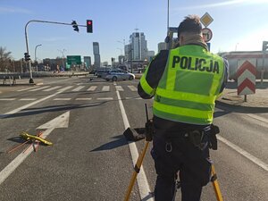 zdjęcie kolorowe: policjant wykonujący pomiary za pomocą tachimetru