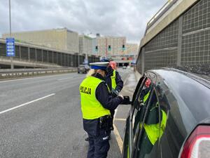 zdjęcie kolorowe: policjanci podczas kontroli drogowej samochodu osobowego