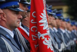zdjęcie kolorowe: poczet sztandarowy i policjanci umundurowani w mundur galowy podczas uroczystej zbiórki